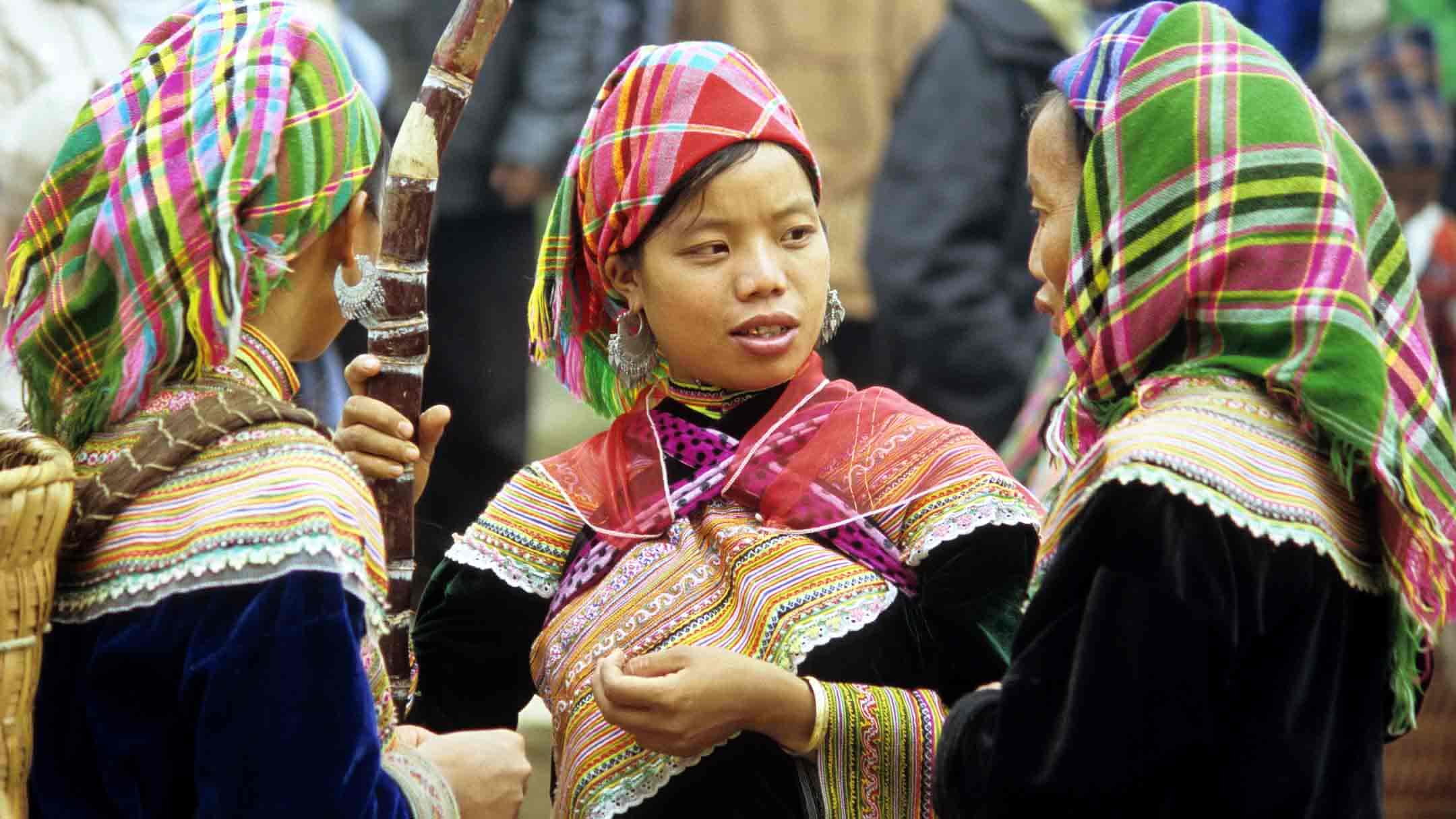 Three traditionally dressed Flower Hmong women talking at the Sunday market, Bac Ha, NW Vietnam